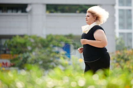 Téléchargez les photos : Curvy jeune femme appréciant le jogging le matin ensoleillé - en image libre de droit