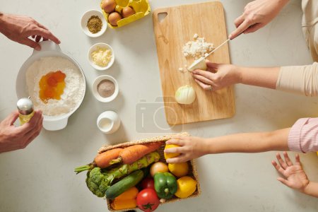 Photo for Hands of family cooking dinner, preparing ingredients, making dough, cutting onion - Royalty Free Image