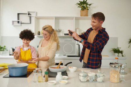 Photo for Excited father photographing his wife and son showing pasta they made for dinner - Royalty Free Image