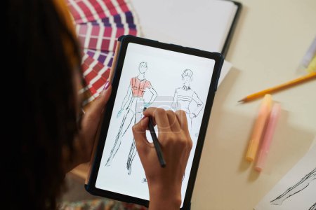 Téléchargez les photos : Image rapprochée d'une artiste féminine coloriant un croquis de mode sur tablette - en image libre de droit