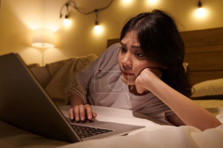 Foto de Chica adolescente leyendo artículos y mensajes en las redes sociales cuando descansa en la cama con el ordenador portátil - Imagen libre de derechos