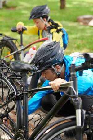 Téléchargez les photos : Les jeunes vérifient leurs vélos avant de faire un long trajet dans le parc de la ville - en image libre de droit