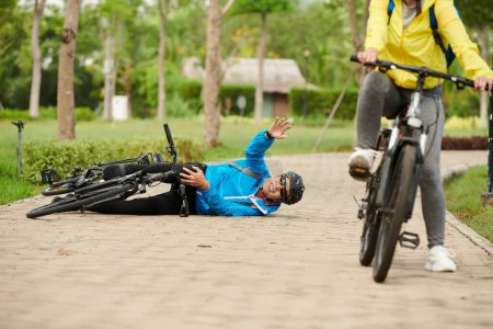 Foto de Hombre pidiendo ayuda después de caerse de la bicicleta y lesionarse la rodilla - Imagen libre de derechos