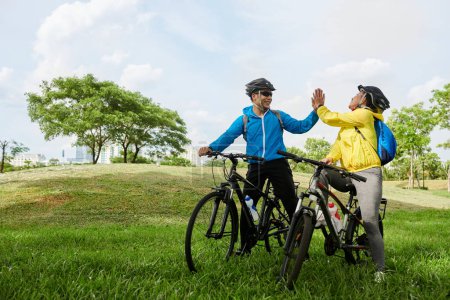 Téléchargez les photos : Des amis joyeux se donnant cinq après avoir fini de venir au point de destination sur les vélos - en image libre de droit