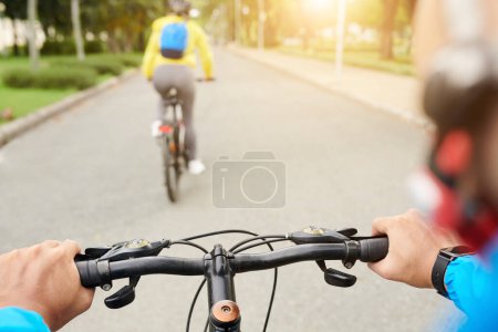 Photo for Young man riding bicycle behind his girlfriend in sunny city park - Royalty Free Image