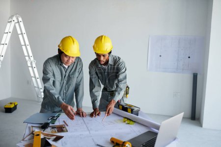 Téléchargez les photos : Travailleurs de la construction discutant du plan de construction sur la table et des travaux de planification - en image libre de droit