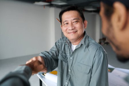Téléchargez les photos : Heureux constructeur vietnamien donnant coup de poing à son collègue après avoir fini de travailler sur le chantier - en image libre de droit
