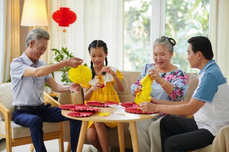 Téléchargez les photos : Famille vietnamienne faisant des décorations pour la célébration du Têt ensemble - en image libre de droit