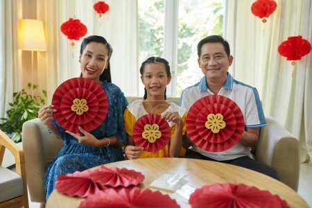 Foto de Familia alegre de tres mostrando decoraciones de papel que hicieron en casa para el festival lunar - Imagen libre de derechos