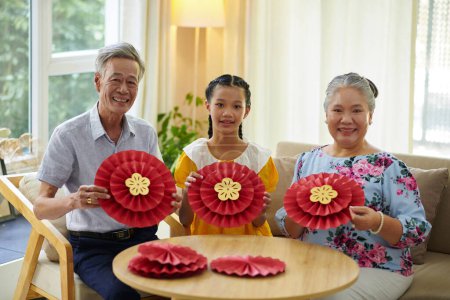 Téléchargez les photos : Adolescente et ses grands-parents aiment créer des décorations en papier pour le festival de printemps - en image libre de droit