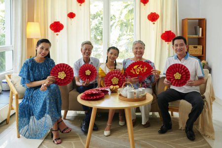 Téléchargez les photos : Heureux famille vietnamienne tenant fans de papier qu'ils ont créé pour la célébration du festival de printemps - en image libre de droit