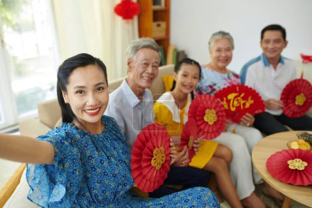 Foto de Mujer sonriente tomando selfie con los miembros de la familia al celebrar el Tet en casa - Imagen libre de derechos
