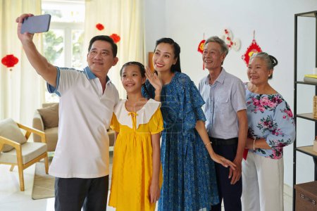 Téléchargez les photos : Bonne famille vietnamienne posant pour selfie de groupe à la fête du Têt - en image libre de droit