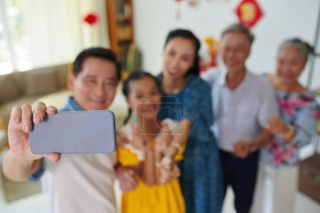 Foto de Familia feliz tomar selfie grupo cuando se celebra Tet en casa, se centran en el teléfono inteligente - Imagen libre de derechos