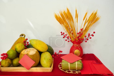 Photo for Tray with fresh fruits, traditional rice cake and lucky money envelopes on table decorated for Tet - Royalty Free Image
