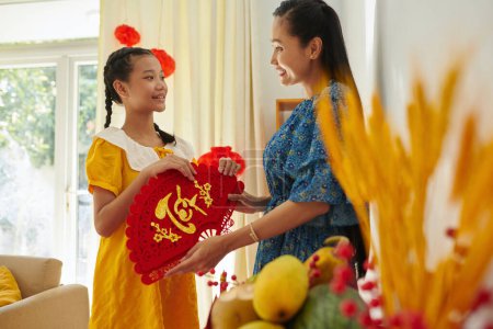 Foto de Sonriente adolescente ayudando a la madre a decorar la casa para la celebración del Tet - Imagen libre de derechos