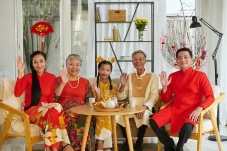 Foto de Retrato de una familia vietnamita feliz tomando té con golosinas al celebrar el Tet en casa - Imagen libre de derechos