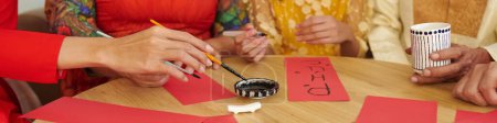 Photo for Header with hands of family members creating calligraphy couplets for Tet holiday - Royalty Free Image