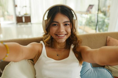 Téléchargez les photos : Adolescente heureuse dans la vidéo casque appelant son ami ou les membres de sa famille - en image libre de droit