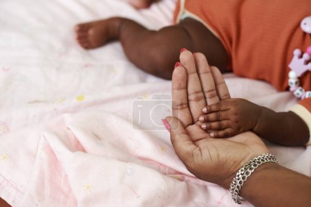 Foto de Manos de madre tocando la manita de su bebé recién nacido - Imagen libre de derechos