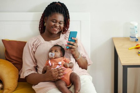 Foto de Alegre mujer negra con recién nacido bebé mensajes de texto amigos - Imagen libre de derechos