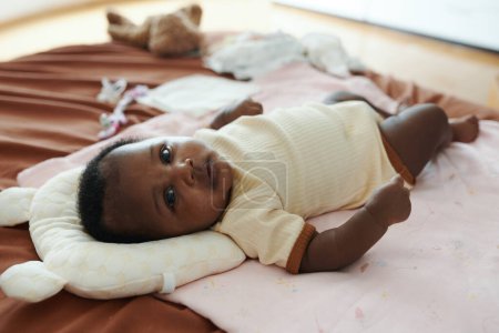 Téléchargez les photos : Adorable bébé fille noire en coton onesie regardant la caméra - en image libre de droit