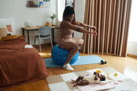 Téléchargez les photos : Mère heureuse du nouveau-né faisant de l'exercice à la maison - en image libre de droit