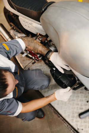 Téléchargez les photos : Mécanicien de moto travaillant dans le garage, vue de dessus - en image libre de droit