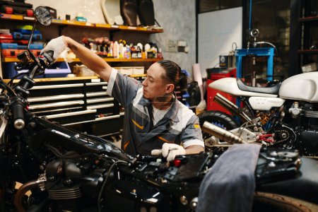 Photo for Mechanic squeezing and holding clutch lever down to check if engine of motorcycle works - Royalty Free Image
