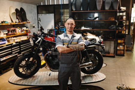 Photo for Portrait of happy motorcycle repair shop owner standing in his garage - Royalty Free Image