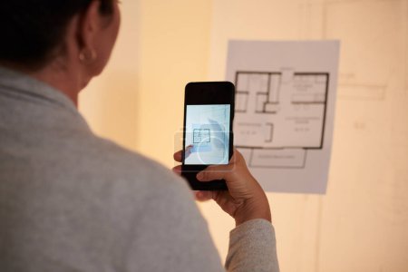 Téléchargez les photos : Image en gros plan de l'architecte prenant une photo du plan de la maison à envoyer à un collègue - en image libre de droit