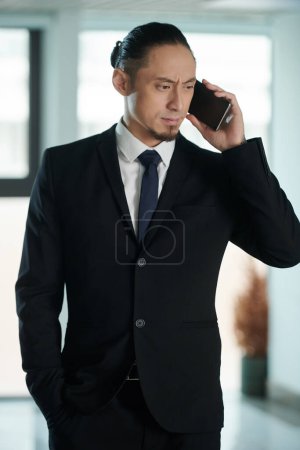 Foto de Frunciendo el ceño preocupado hombre de negocios hablando por teléfono con su socio de negocios - Imagen libre de derechos