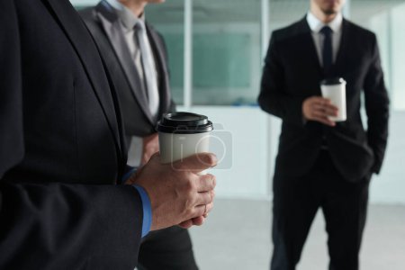 Téléchargez les photos : Cropped image of business people drinking take out coffee when spending break in office hall - en image libre de droit