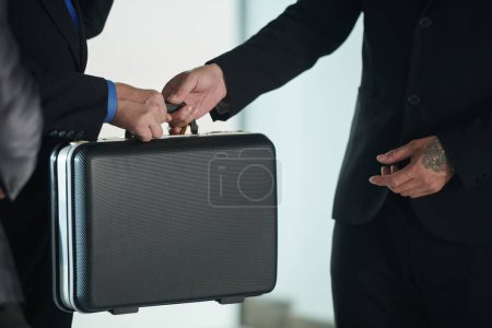 Photo for Cropped image of businessman giving briefcase with product or money to investor or business partner - Royalty Free Image