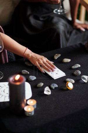 Photo for Young woman using tarot cards and rune stones for divination practice at home - Royalty Free Image