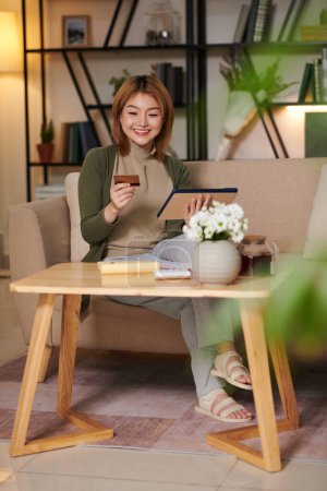 Téléchargez les photos : Portrait de jeune femme asiatique heureuse faisant du shopping en ligne et payant par carte de crédit - en image libre de droit