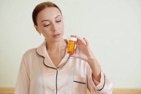 Photo for Young woman holding container with birth control pills - Royalty Free Image