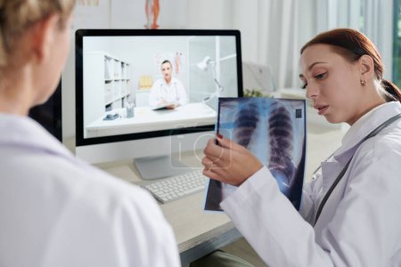Foto de Equipo de médicos discutiendo deporte oscuro en los pulmones radiografía del paciente - Imagen libre de derechos