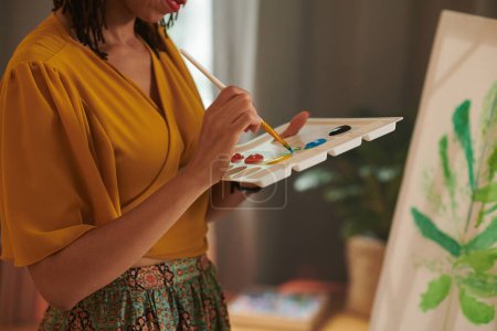 Foto de Imagen recortada del pintor femenino mezclando colores en la paleta para obtener el verde perfecto para su pintura - Imagen libre de derechos
