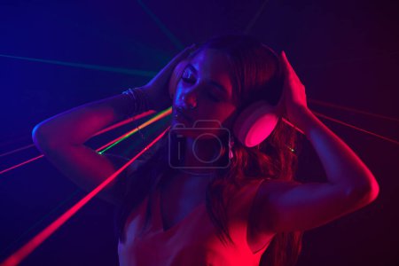 Foto de Mujer en auriculares bailando en luces de neón en club nocturno - Imagen libre de derechos