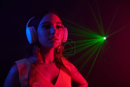 Téléchargez les photos : Portrait de jeune femme dans un casque travaillant comme DJ dans une boîte de nuit - en image libre de droit