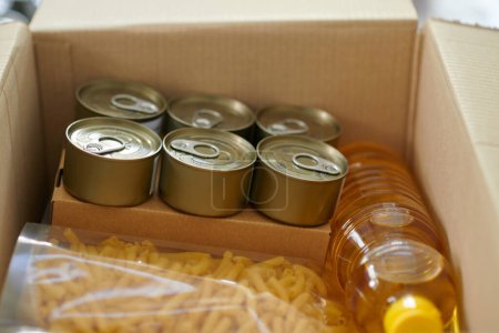 Photo for Box with canned food, vegetable oil and macaroni packed for family in need - Royalty Free Image