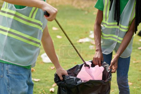 Téléchargez les photos : Image recadrée de volontaires jetant des ordures dans des big bags - en image libre de droit