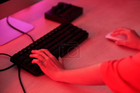 Photo for Closeup image of child playing videogame on computer in neon room - Royalty Free Image