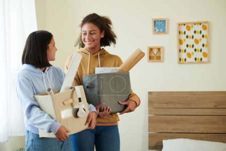 Photo for Smiling teenage roommates with boxes of belongings meeting each other for the first time - Royalty Free Image