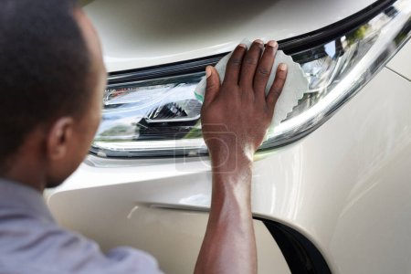 Photo for Closeup image of car owner wiping headlights with soft microfiber cloth - Royalty Free Image