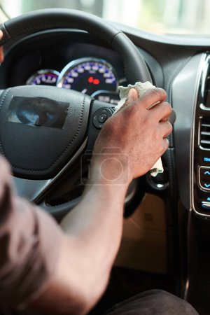 Photo for Closeup image of driver wiping steering wheel with antibacterial detergent - Royalty Free Image