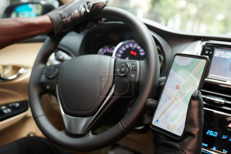 Téléchargez les photos : Image rapprochée du chauffeur de taxi vérifiant la carte sur smartphone lors de la conduite du client - en image libre de droit
