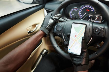 Foto de Manos del conductor de automóviles de lujo siguiendo el mapa en el teléfono inteligente al conducir a los pasajeros - Imagen libre de derechos