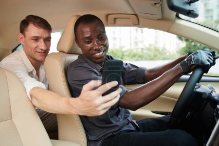 Téléchargez les photos : Passager montrant le point de destination sur la carte au chauffeur de taxi - en image libre de droit
